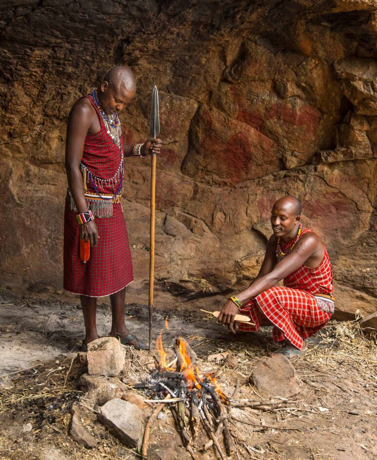 Two tribes men stand above a fire
